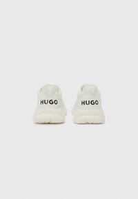 Hugo branded sneakers in light cream with a smooth texture, featuring a chunky sole and rear logo detail in black.