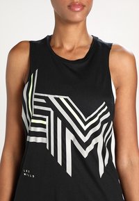 Black sleeveless athletic top featuring a geometric white and neon green pattern, made from textured fabric, with "LES MILLS" branding.