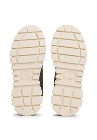 Semelles en caoutchouc beige chunky avec de profondes rainures et le logo "Tommy Jeans" embossé au milieu.