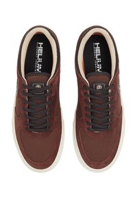 Sneaker in suede marrone con lacci neri, interno crema e suole in gomma bianca. Presenta un logo laterale e una texture in tessuto su tutta la superficie.