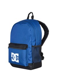 Blue fabric backpack with a black bottom, zippered front pocket, mesh side pocket, and white DC logo on the front panel. Padded straps.