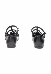 Scarpe nere con finitura in pelle liscia, caratterizzate da un design a taglio e borchie sollevate lungo le cinghie. Suola piatta con tacco minimo.