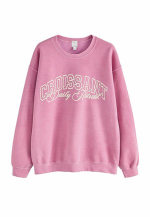 Pink sweatshirt with a crew neck, long sleeves, and white "CROISSANT Daily Ritual" text. Features a soft texture and casual fit.