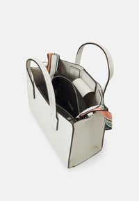 Sac à main en cuir blanc avec deux poignées, pochette intérieure noire avec fermeture éclair et un accent tissé coloré sur le côté.