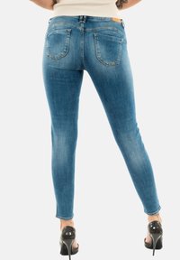 Jeans ajustados en denim azul claro, con una altura media, cinco bolsillos, un sutil desvanecimiento y una textura suave. Diseño de ajuste slim hasta el tobillo.