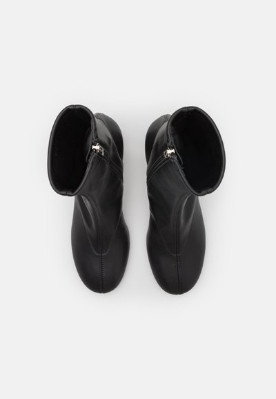 Svarta läderankelboots med glänsande finish, utrustade med dragkedjestängning och en elegant, slimmad design med synliga sömmar.