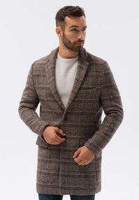 Ruskea ruutukuosiset takki, jossa on muotoiltu leikkaus, viistopäiset liepeet ja yhden napin suljenta. Takissa on etutaskut ja teksturoitu kangas.