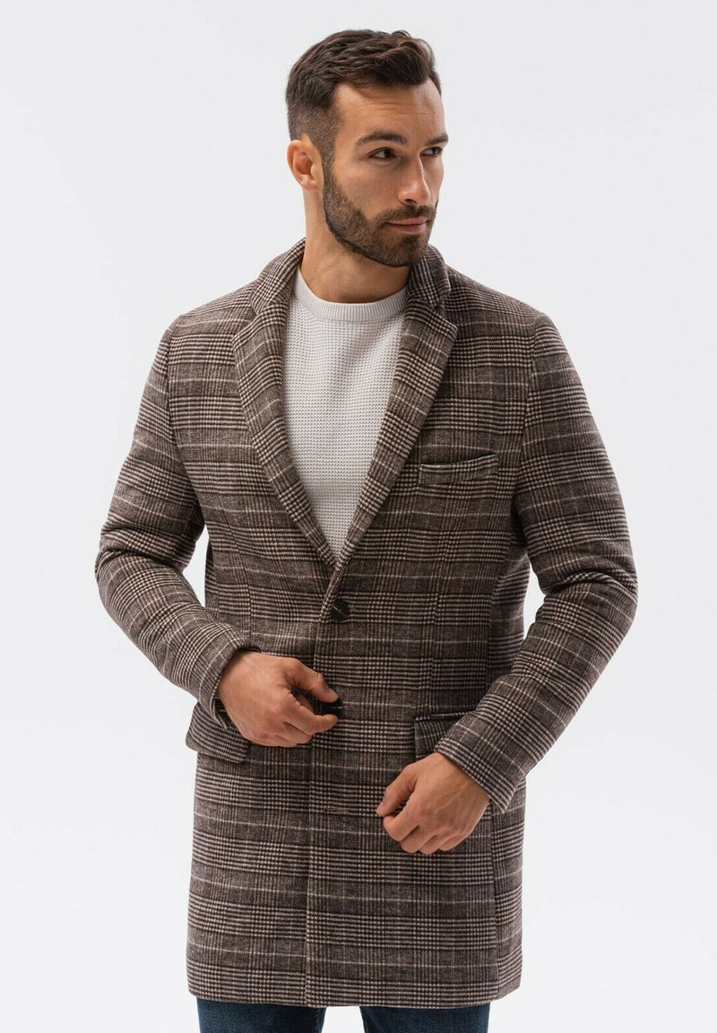 Ruskea ruutukuosiset takki, jossa on muotoiltu leikkaus, viistopäiset liepeet ja yhden napin suljenta. Takissa on etutaskut ja teksturoitu kangas.