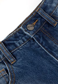 Dżinsy z denimu z zapięciem na guzik, zdobione srebrnym logo Gulliver, niebieskie z widocznym przeszyciem i lekko spranym efektem.