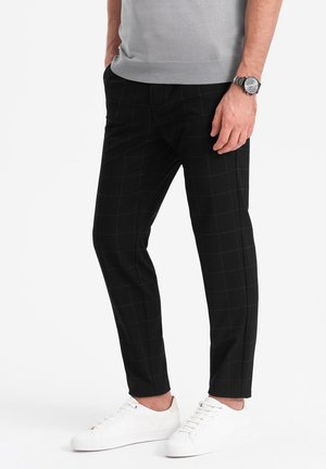 Czarne spodnie w kratę o slim fit, wykonane z miękkiego materiału. W zestawie z białymi sneakerami; subtelne detale w pasie i elegancki design.