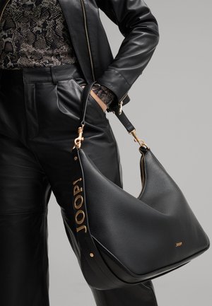 Black leather shoulder bag with a textured finish, gold hardware accents, and embossed logo "JOOP!" on the strap. Curved, modern shape.