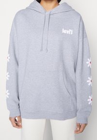 Šedá mikina s kapucí a klokaní kapsou, bílým logem "Levi's" a květinovou výšivkou v bílé a červené na rukávech. Měkká tkanina.