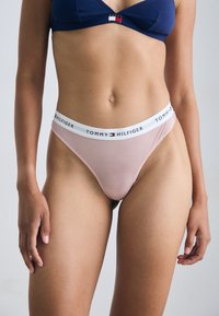 String rose clair avec des rayures et une taille avec le logo Tommy Hilfiger. Tissu doux avec un ajustement confortable, conçu pour un port moderne.