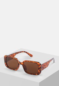 Okulary przeciwsłoneczne w kolorze tortoise z kwadratowymi soczewkami, brązowymi soczewkami, grubą oprawką i smukłymi ramionami. Posiadają błyszczącą fakturę oraz srebrne akcenty.