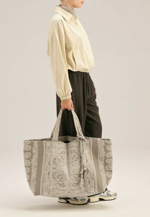 Torebka typu tote w szaro-białym wzorze paisley z dwiema fakturowanymi uchwytami. Torba ma przestronny design oraz kontrastowe poziome paski.