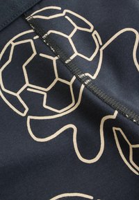 Tissu noir avec un motif abstrait blanc hexagonal et de lignes courbes, traversé par une couture noire au centre.
