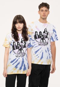 T-shirt featuring a tie-dye pattern in blue, purple, and yellow with a black graphic of five figures and "Aerosmith" text. Short sleeves, relaxed fit.