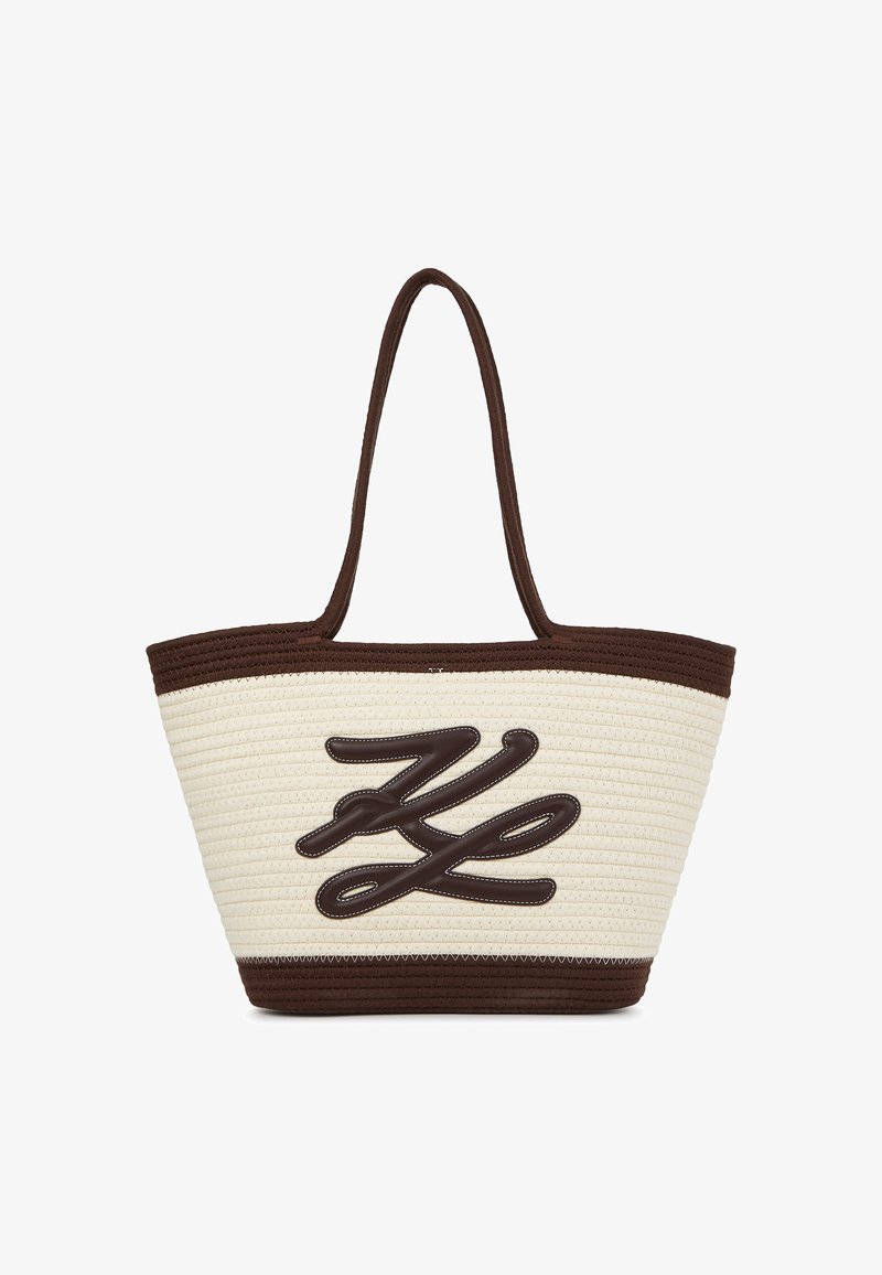 Austo aušanas salmu soma ar brūniem akcentiem, ar drosmīgu, teksturētu logo dizainu krēmkrāsas pamatē un divām izturīgām rokturiem.