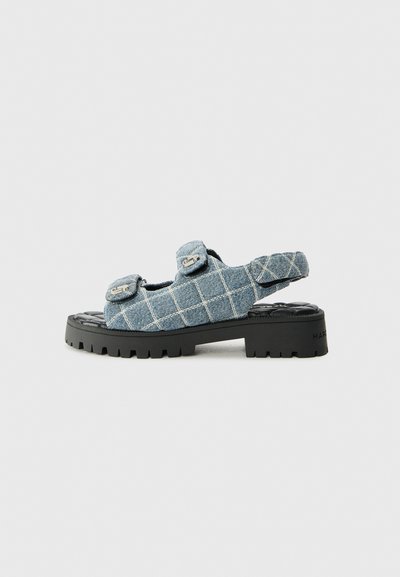 Sandali in denim con motivo a scacchi, due cinturini regolabili e una suola piatta nera chunky. Parte superiore testurizzata con dettagli sintetici.