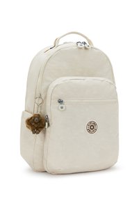 Beiger Rucksack mit abgerundetem Design, aus synthetischem Material. Verfügt über eine Vorderseite mit Tasche und einen Affen-Schlüsselanhänger. Logo auf der Vorderseite.