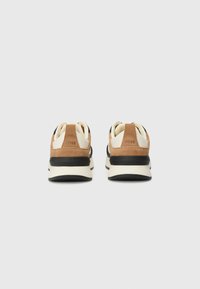 Le sneakers presentano una combinazione di suede marrone e materiale sintetico nero, con una suola crema e un logo prominente sul tallone. Design alla moda e texture.