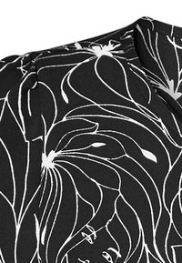 Tessuto nero con grandi motivi floreali bianchi e una consistenza liscia. Presenta un dettaglio con scollatura plissettata.