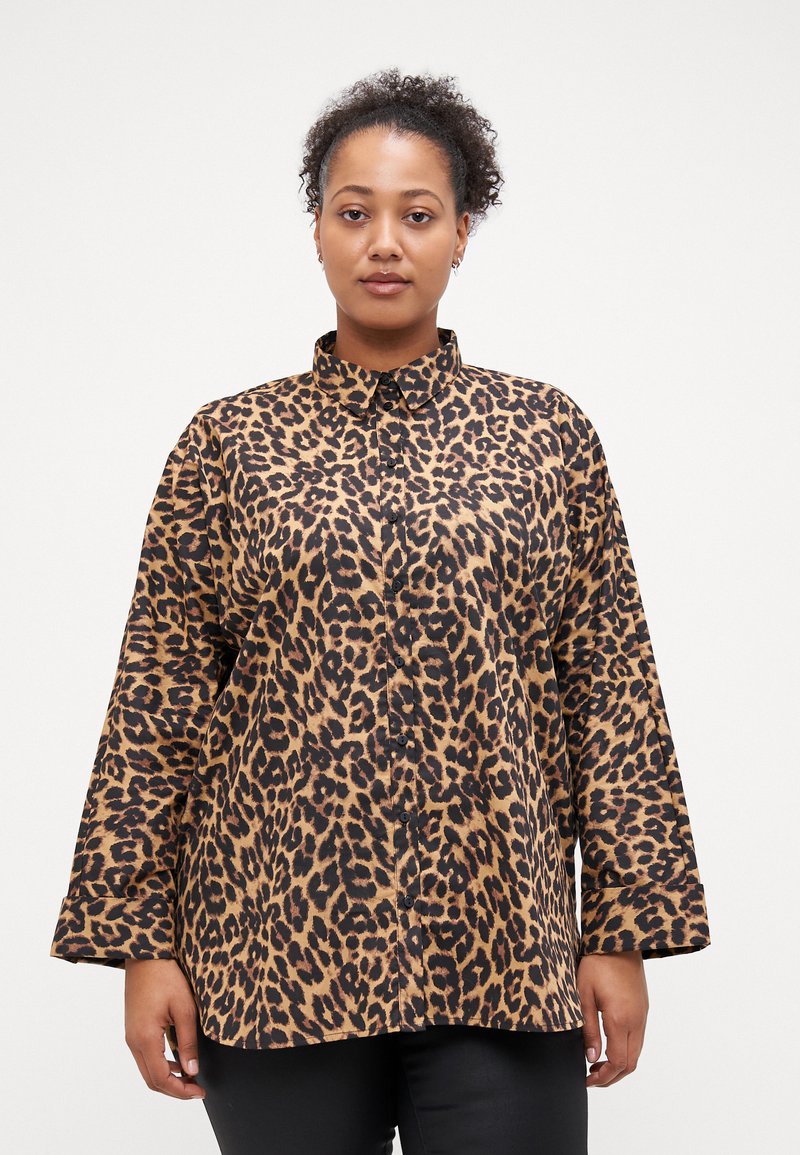 Chemise en coton imprimé léopard beige et noir avec col, manches longues, fermeture boutonnée à l'avant et coupe ample.