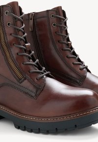 Bottines en cuir marron avec une finition lisse, dotées d'une fermeture éclair sur le côté, d'un devant lacé et d'une semelle en caoutchouc noir texturé pour une meilleure adhérence.