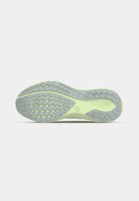 Semelle d'une chaussure de course vert clair avec des motifs d'adhérence texturés gris et un petit logo Nike près du talon.