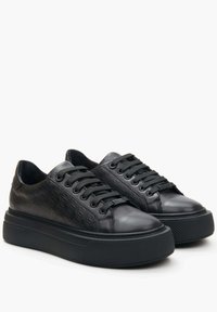Black sneakers with a smooth leather and textured upper, featuring a patterned design, round toe, and a thick rubber sole.