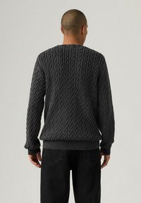 Dark gray knitted sweater with a textured cable pattern, ribbed cuffs and hem, round neckline, and a relaxed fit.