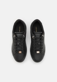 Czarne sneakersy wykonane z gładkiej skóry, z sznurowanym zapięciem, metalowymi otworami na sznurówki oraz małym logo po bokach.