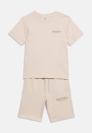 Béžové tričko s krátkým rukávem a odpovídající šortky s logem Jack & Jones Archive Selection na hrudi a levé noze.