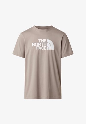 Camiseta beige de manga corta hecha de algodón, con un gran logo blanco de "The North Face" en el frente. Diseño sencillo y clásico.