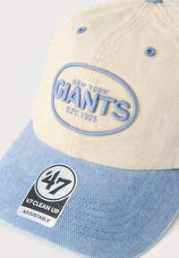 Μπεζ και γαλάζιο ρυθμιζόμενο καπέλο μπέιζμπολ με κεντημένο μπλε κείμενο στην πρόσοψη που γράφει "New York Giants Est. 1925".