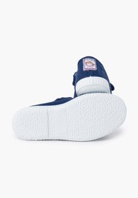 Scarpa in tessuto blu con suola in gomma bianca, caratterizzata da un'etichetta cucita sul tallone. Il design include una parte superiore morbida e testurizzata per il comfort.