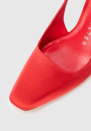 Scarpa con tacco alto in raso rosso, con punta affusolata e lato sagomato, caratterizzata da una superficie liscia e una fodera interna lucida.