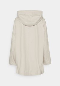 Veste à capuche beige avec une coupe ample, dotée d'une coupe droite, de coutures d'épaule et d'une texture lisse. Vue de dos sans fermetures visibles.