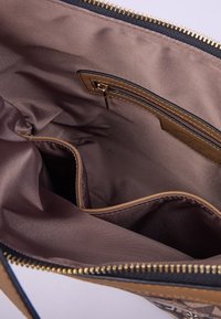 Tan og brun indvendig i en lynlåset håndtaske, med en glat tekstur, en lynlåslomme og flere rum til organisering.