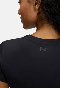 Schwarzes Sport-T-Shirt mit glatter Textur, kurzen Ärmeln und rundem Ausschnitt. Mit einem dezenten, dunklen Under Armour-Logo auf der Rückseite.