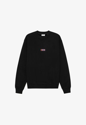 Črni pulover z okrolim izrezom in dolgimi rokavi ter majhnim pravokotnim večbarvnim napisom "LES DEUX" na sredini prsnega koša.