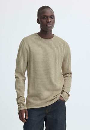 Olivengroen shirt met lange mouwen, een horizontale geribde textuur, een ronde hals en een licht ontspannen pasvorm, gecombineerd met donkere spijkerbroek.