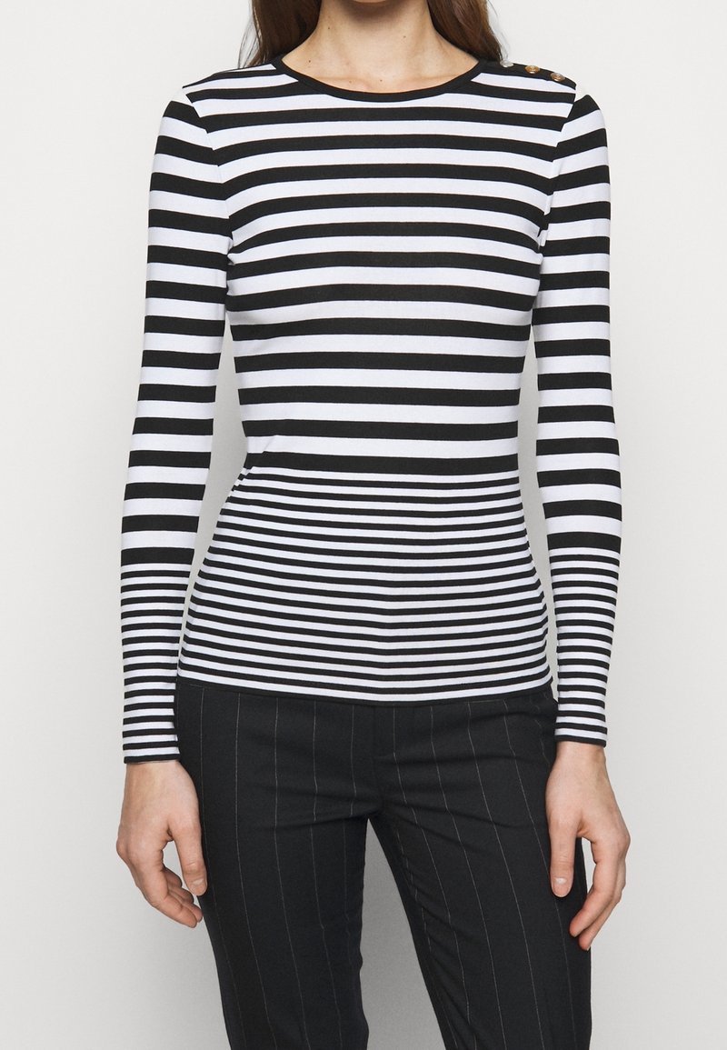 Black and white striped long-sleeve top with a round neckline and button accents on the shoulder, made of a smooth fabric.