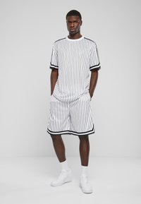 Hvit og svart stripete kortermet skjorte og matchende shorts med svart trim, laget av lett stoff; stylet med lommer og avslappet passform.