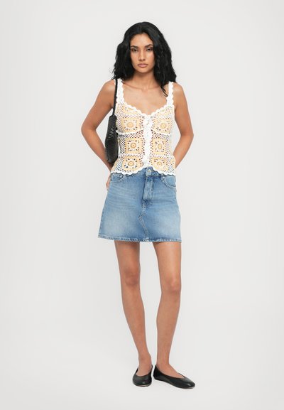 Top croșetat cu modele pătrate galbene, decolteu cu valuri; asortat cu o fustă din denim de un albastru deschis și balerini negri.