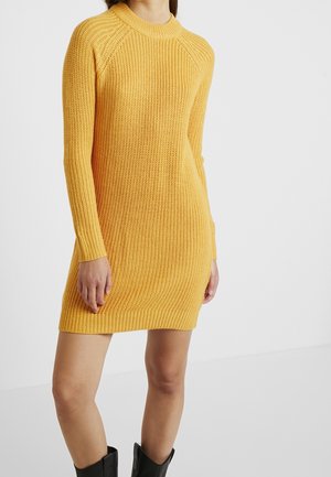 Gelbes gestricktes Kleid mit gerippter Textur, langen Ärmeln und einem runden Ausschnitt. Es passt eng und fällt oberhalb des Oberschenkels.