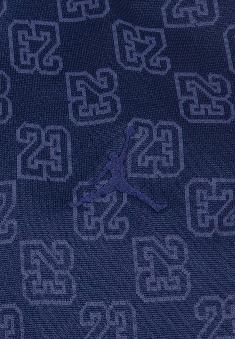Tissu navy avec un motif en relief de "23" et "N" de tailles variées, mettant en avant un logo Jordan en relief et de contraste.
