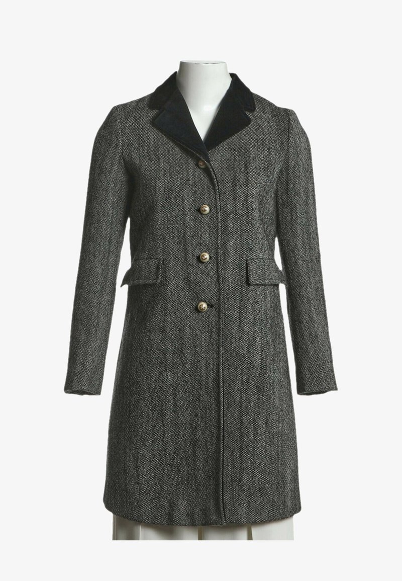 Long manteau gris en chevron avec col en velours noir, quatre boutons sur le devant, et deux poches à rabat à la taille.