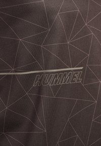 Mørkt stoff med et geometrisk linjemønster og ordet "HUMMEL" sentrert, ledsaget av en horisontal linje over teksten.