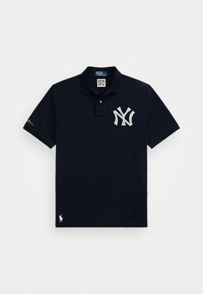Marineblå polo skjorte laget av bomull, med et stort hvitt NY-logo på brystet, et lite logo nær kanten, og tre-knapps placket.